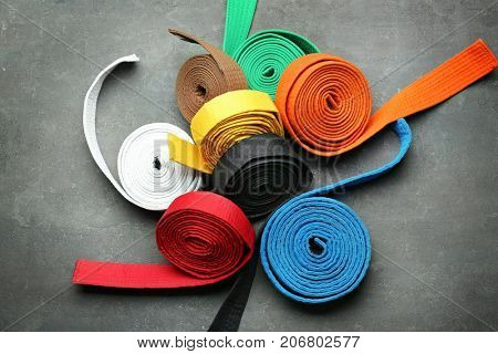 Colorful karate belts on grey background