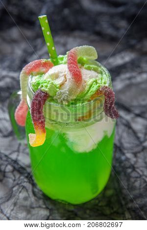 Green drink with ice cream float and gummy worms for Halloween party