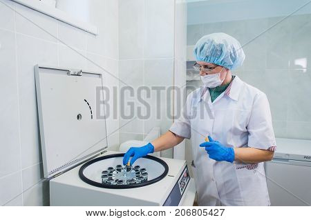 Closeup of a senior female chemist setting up some sample blood tubes inside a centrifuge for some test in a lab