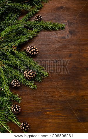 flat lay chrismas rpattern larch and fir branches and pine cones on the wood desk. Empty space for text.