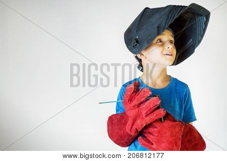 Happy little kid in welder mask and welding equipment. Welding equipment welding mask protective leather gloves welding electrodes. Fun concept. Child dreaming of future profession. Career choice.