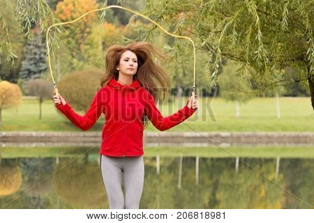 Portrait Of Fit Young Woman With Jump Rope In A Park. Fitness Female Doing Skipping Workout Outdoors