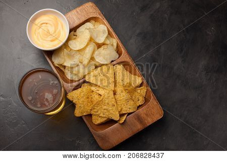 Beer In Glasses Closeup On The Concrete Table. Beer And Snacks Are Chips And Nachos In Wooden Bowl W