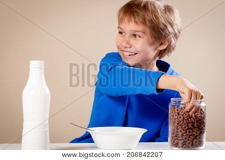 Child eating cereal with milk for breakfast at home