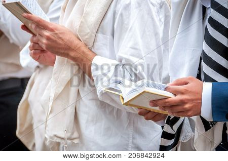 Hands and prayer book close-up. Orthodox hassidic Jews pray in a holiday robe and tallith.