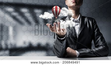 Closeup of business woman in suit presenting flying aerostate among clouds in her palm with office view on background. 3D rendering.