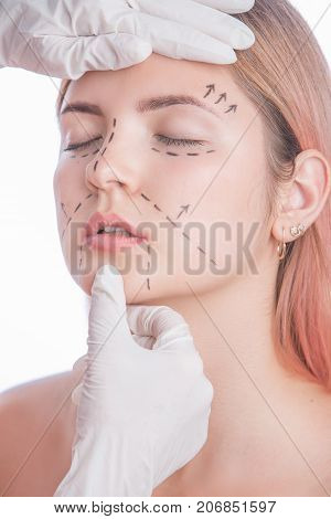 Young pretty girl with perforation lines on face and doctors hands. Isolated on white