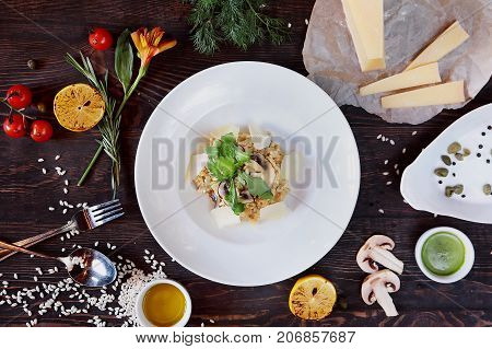 risotto with mushrooms, parmesan cheese and vegetables on wooden table with spices