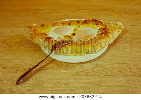 Khachapuri raditional Georgian cheese-filled bread Ajarian style. Adjarian khachapuri with eggs on the table - Retro color