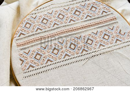 Embroidered fragment on flax by brown and beige cotton threads. Embroidery texture flat stitch. Ukrainian ethnic ornament. Hemstitch.