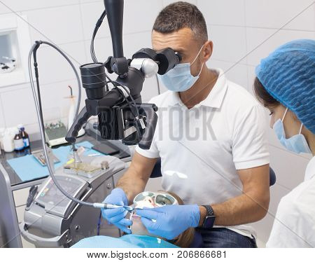 Doctor dentist treats teeth of a beautiful young girl patient. The girl on reception at the dentist. Doctor dentist treats tooth.