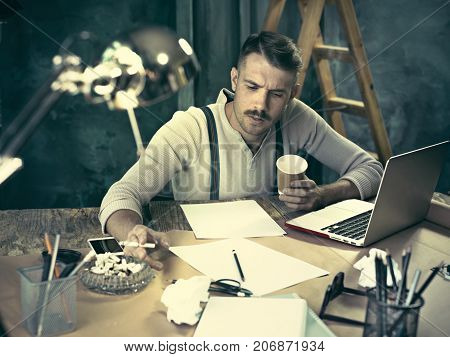 The Handsome Elegant Man Sitting At Home Table, Working And Usin