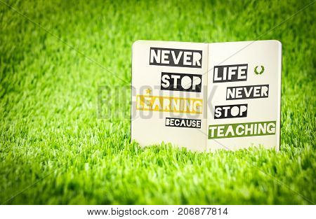 .Inspiration quote Never stop learning because life never stop teaching word on book on green greass Motivational typographic