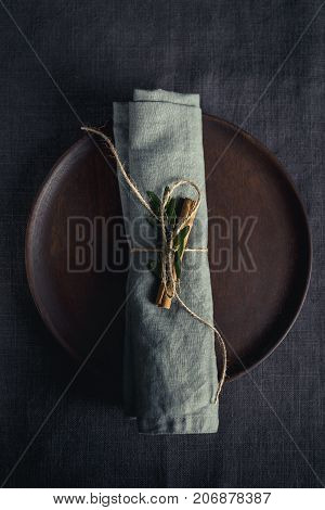 Top view of wooden plate with plain napkin wrapped and decorated with cinnamon stick.