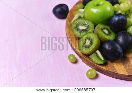 composition of kiwi, grape and apple on a pink background