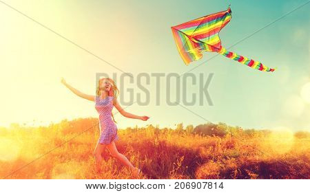 Beauty autumn girl running with kite on the field. Beautiful young woman with flying colorful kite over clear blue sky. Fall. Free, freedom concept. Emotions, healthy lifestyle