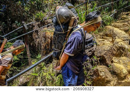 Ranau,Sabah-March13,2016:Mountain porter carrying a heavy backpack to Laban Rata of the majestic Mount Kinabalu in Ranau,Sabah Borneo,Malaysia.