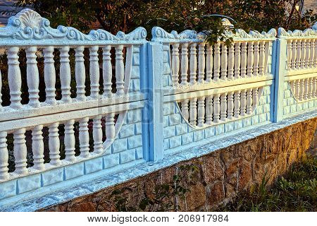 Part of a bright colored concrete fence in green vegetation