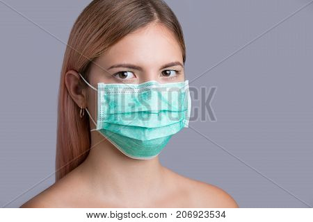 Young pretty girl wearing face protective mask. Isolated on grey