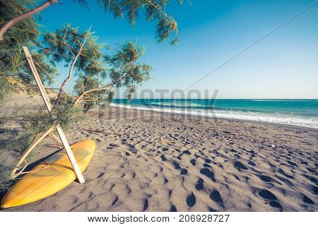 Surf board on the tropical sandy beach of Ligres, Crete, Greece, with big waves.