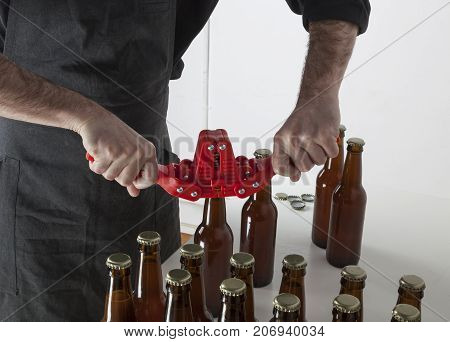 Home brewing: a craft beer brewer closing the bottles with a bottle capper.