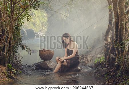 A beautiful Village women sitting and washing the clothes at the stream of waterfall or river countryside and Folkways concept