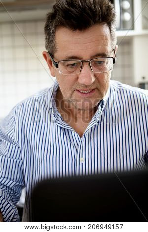 Senior man working on laptop computer at home.