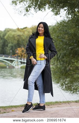 Young brunette woman in gray woolen coat on background autumn park