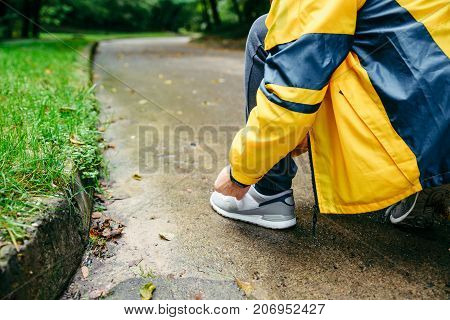 Running and sport concept.Sportsman hands tying shoelaces. autumn rainy day