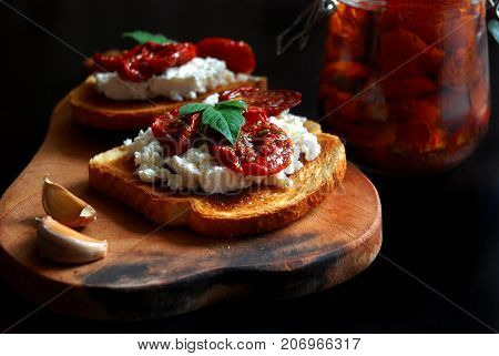 Toast with cheese, garlic and sun-dried tomatoes on a wooden Board.