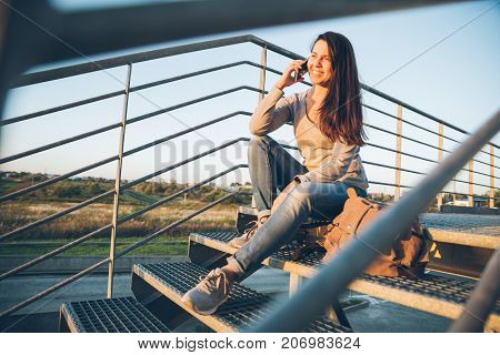 young pretty woman sitting on the stairs of the mall on sunset