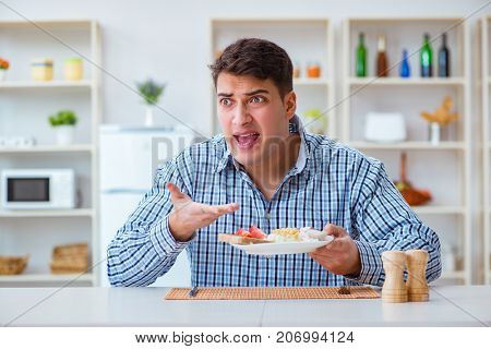 Young husband eating tasteless food at home for lunch