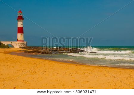 Salvador, Bahia, Brazil: Farol De Itapua On The Rough Sea. Lighthouse On The Beach In Sunny Weather.