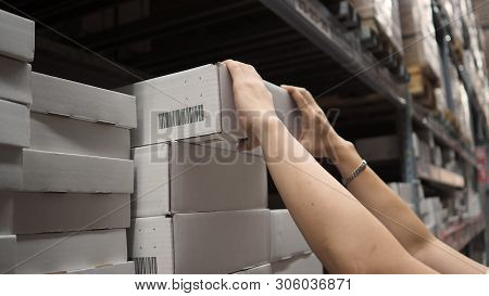 Warehouse Large Storage Or Logistic Or Cargo For Distribution. And Man's Hand Is Picking Up A Box.