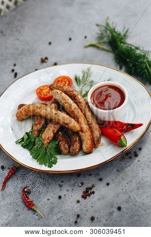 Grilled Sausages With Stewed Cabbage, With Pepper Sauce Ketchup, Chilli, Mustard On A White Plate, O