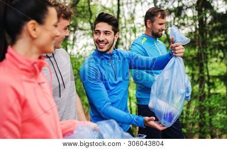 Group Of Fit People Picking Up Litter In Nature, A Plogging Concept.