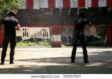 Military Shooting Range With Two Men Firing Weapons In The Foreground