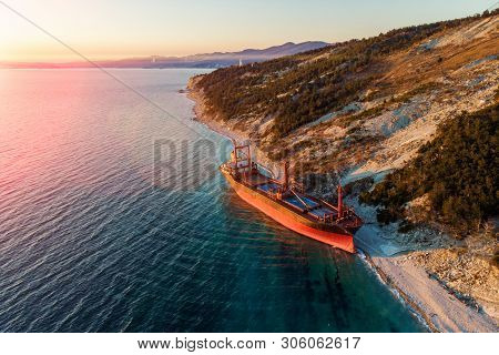 Aerial View Of Cargo Ship Run Aground On Wild Coast, Shipwreck After Storm, Drone Shot