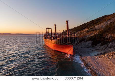 Aerial View Of Cargo Ship Run Aground On Wild Coast, Shipwreck After Storm, Drone Shot