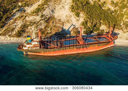 Aerial View Of Cargo Ship Run Aground On Wild Coast, Shipwreck After Storm, Drone Shot