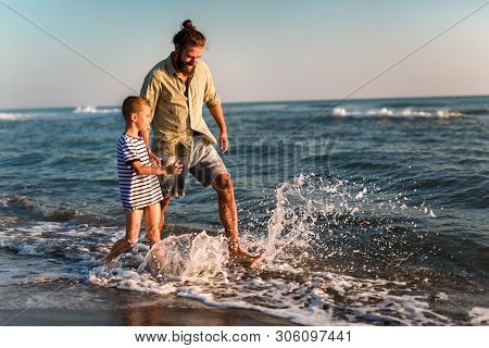 Happy Father And Son, Man & Boy Child, Running And Having Fun In The Sand And Waves Of A Sunny Beach