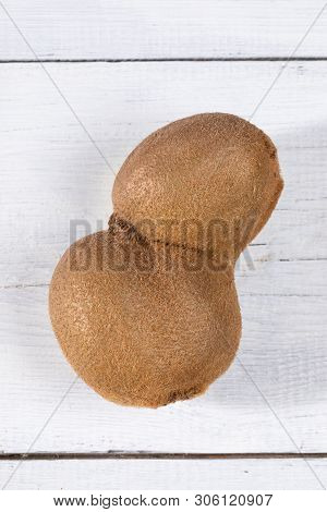 Close-up Single Deformed Conjoined Ugly Kiwi On White Painted Wooden Table.