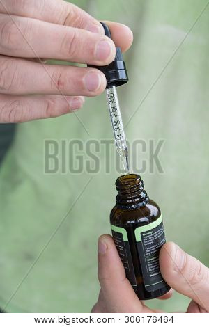 Measuring The Correct Amount Of Cbd Oil From A Brown Tincture Bottle.