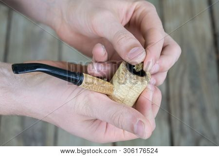 Caucasian Male Packing A Corn Cobb Pipe With Marijuana.