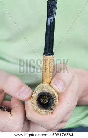 Caucasian Male Packing A Corn Cobb Pipe With Marijuana.