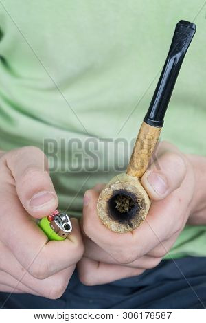 Caucasian Male Packing A Corn Cobb Pipe With Marijuana.