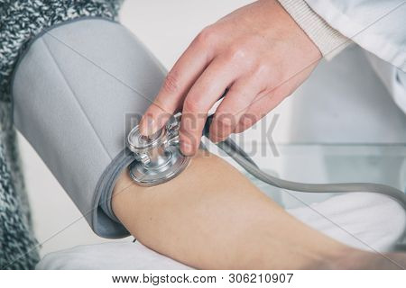 Doctor cardiologist measuring blood pressure of female patient in hospital office appointment