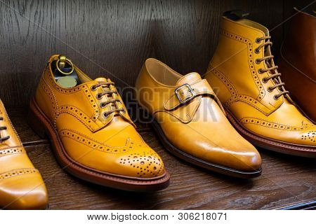Tan full grain leather brogues shoes set on wooden display in in men shoes boutique store.