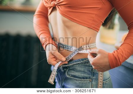 Woman Stands And Measures The Girth Around Her Waist By The Measuring Tape. The Concept Of Diet And 