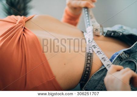 Woman Lies And Measures The Girth Around Her Waist By The Measuring Tape. The Concept Of Diet And He